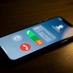 Smartphone posé sur un bureau sombre, affichant une notification abstraite d’appel manqué dans une ambiance domestique sobre associée à la cybersécurité.