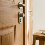 Porte d’entrée réaliste d’un appartement en location avec cylindre de serrure européen visible et trousseau de clés posé sur une table en bois, éclairée par la lumière naturelle.