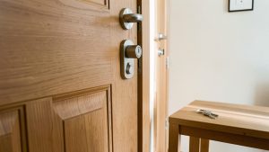 Porte d’entrée réaliste d’un appartement en location avec cylindre de serrure européen visible et trousseau de clés posé sur une table en bois, éclairée par la lumière naturelle.