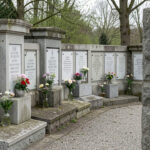 Les 6 meilleurs compromis face aux fleurs des columbariums tournaisiens en 2026 Vue sobre d’un columbarium dans un cimetière belge, avec des plaques funéraires alignées et de petites fleurs dans des vases intégrés, sous une douce lumière printanière.